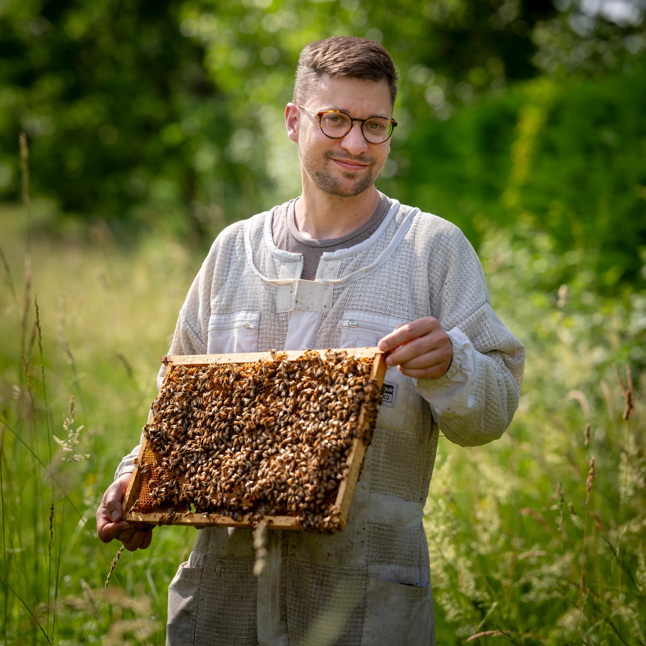 Benoît Serre apiculteur du Rucher du Marandou tenant un cadre de ruche en Dordogne