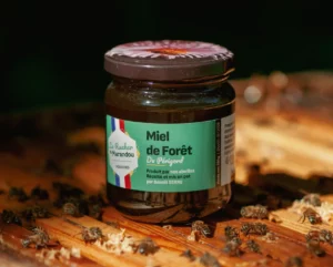 Pot de miel de forêt 250 g du Rucher du Marandou posé sur une ruche avec des abeilles en Dordogne.