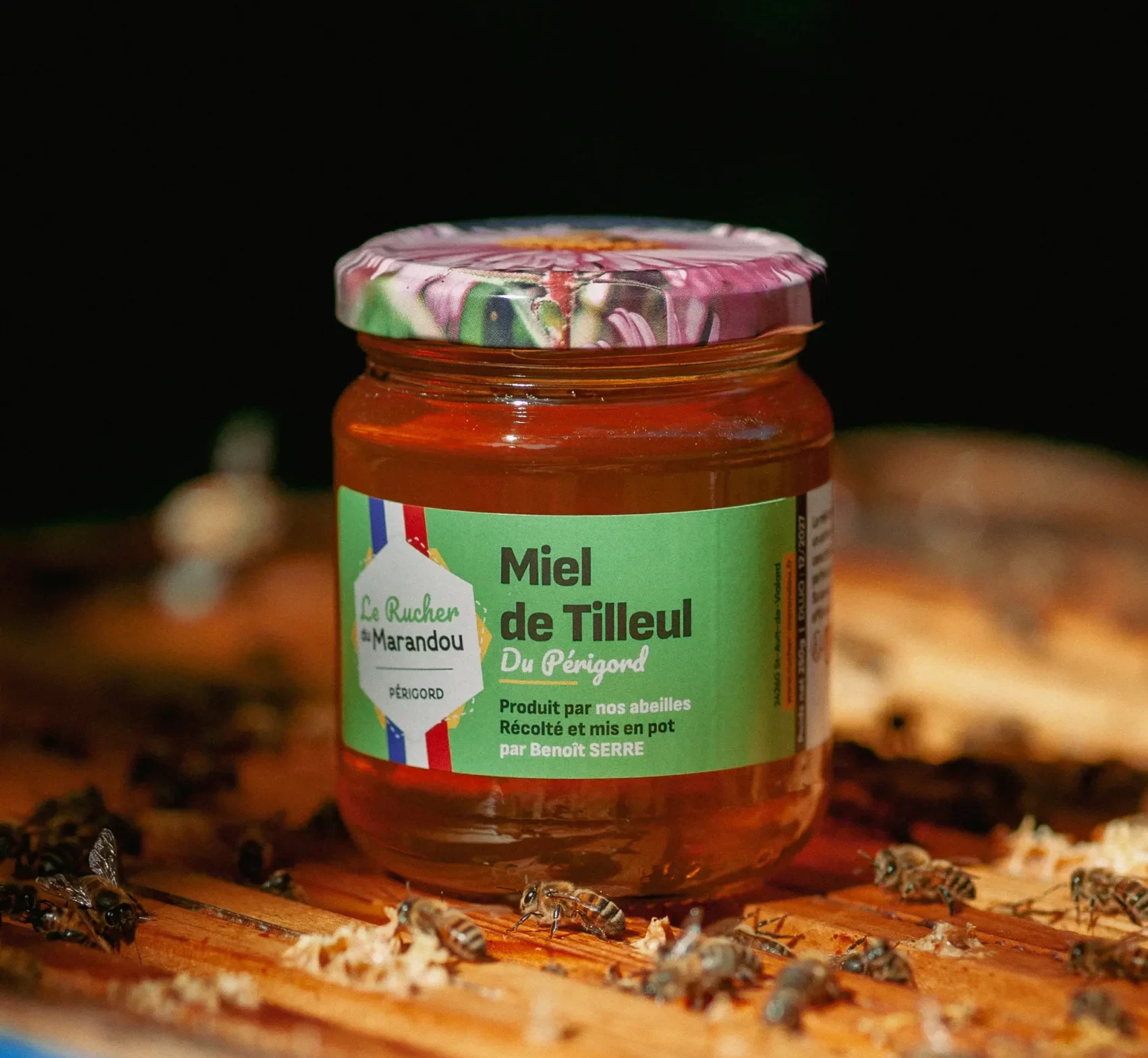 Pot de miel de tilleul du Périgord 250 g posé sur une ruche avec des abeilles