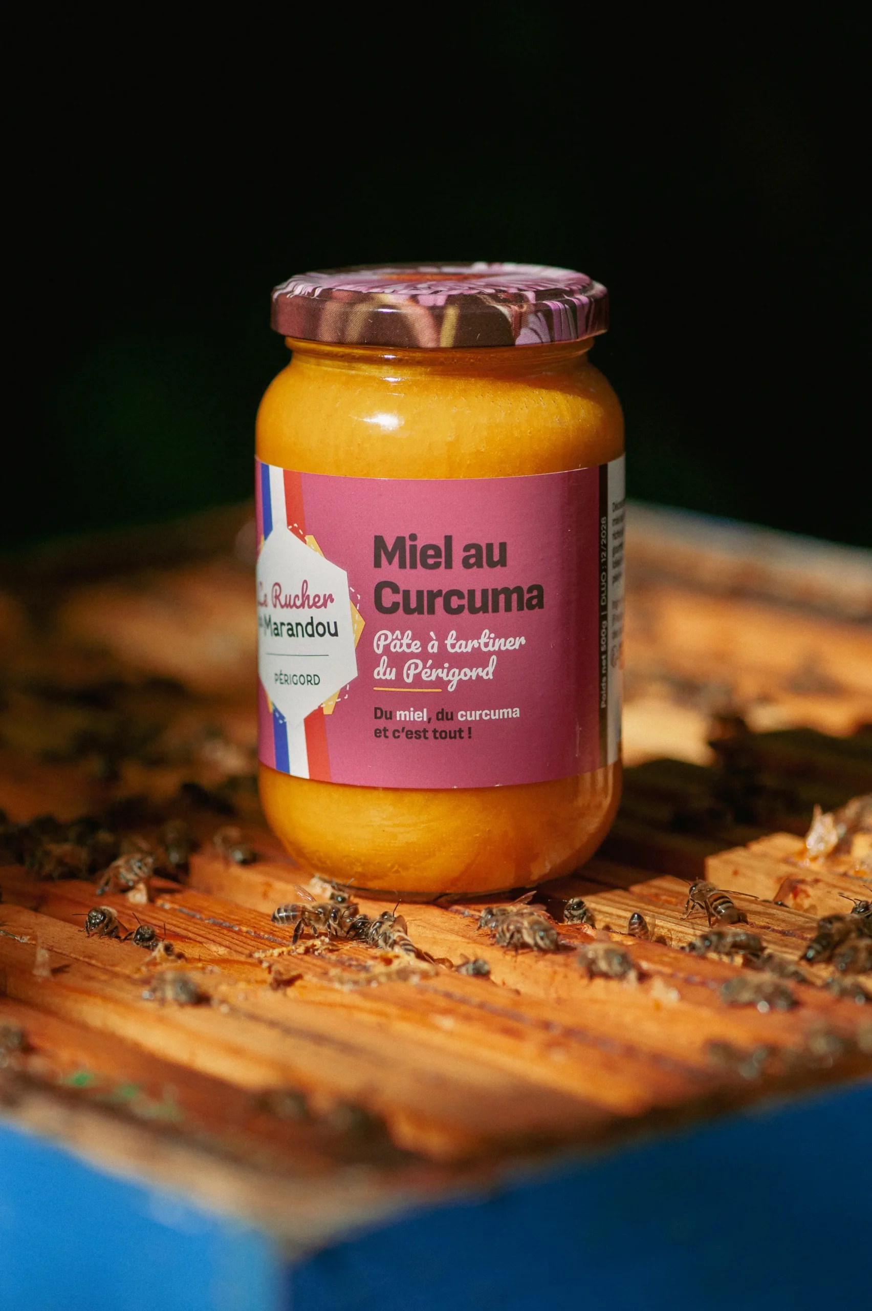 Miel au curcuma 500 g – Rucher du Marandou – Dordogne Pot de miel au curcuma 500 g du Rucher du Marandou posé sur une ruche, entouré d’abeilles en Dordogne