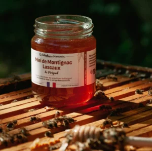 Pot de miel Montignac Lascaux posé sur une ruche avec des abeilles – Rucher du Marandou.