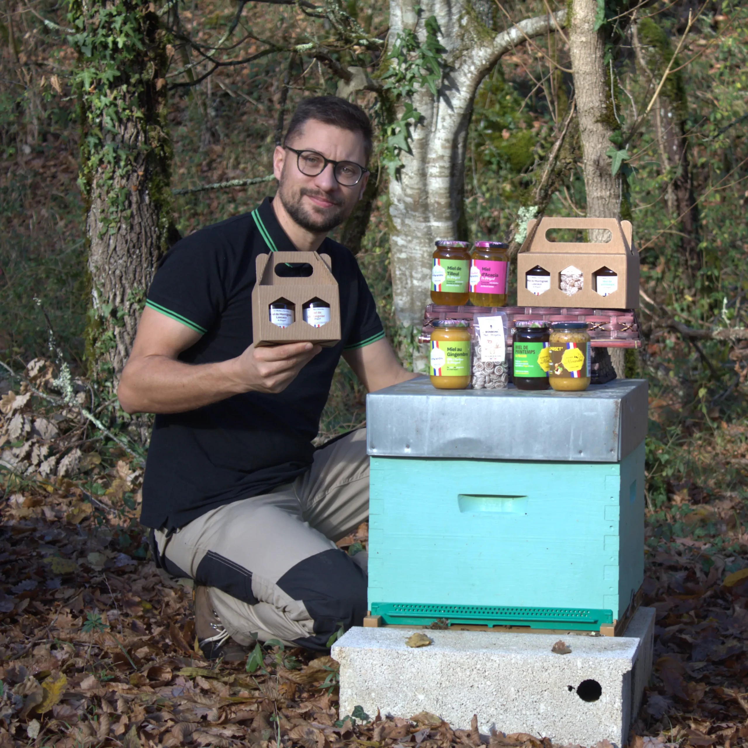 Apiculteur du Rucher du Marandou présentant sa gamme de miels, bonbons et pâtes à tartiner devant un rucher en Dordogne