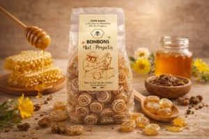 Bonbons au miel et à la propolis artisanaux, issus du miel du Périgord, présentés dans leur sachet avec miel et alvéoles en arrière-plan