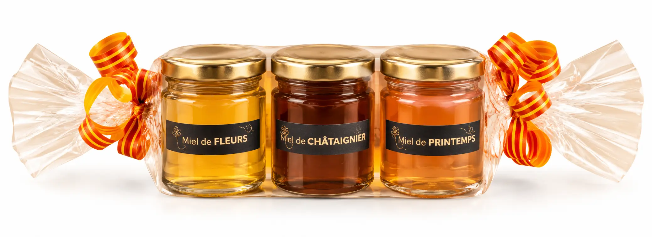 	Trois pots de miel artisanal de 125 g présentés dans un emballage cadeau transparent avec rubans orange